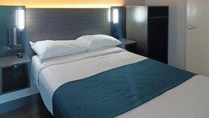 Une chambre d’hôtel comprenant un lit, des tables de chevet, une armoire et des lampes fixées au mur.