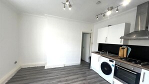 Eine moderne Küche mit Waschmaschine, Backofen und Dunstabzugshaube aus Edelstahl.