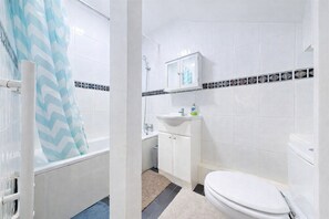 A bathroom with a bathtub, a toilet, a sink, and a shower. - Discover this spacious living space King’s Cross (London)