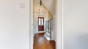 Ein Flur mit Holzboden, einer Treppe und einer Tür mit satiniertem Glas.