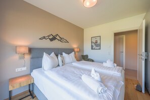 Ein Hotelzimmer mit zwei Betten, einem Nachttisch, einer Wandlampe und einer Tür zu einem anderen Raum.