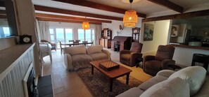 Amplia sala de estar con chimenea, comedor con vistas y zona de cocina.