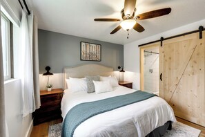 A bedroom with a bed, bedside lamps, a ceiling fan, a wooden wardrobe, and a window with curtains. - Hot Tub/Pool/Near Lake/Whitefish Resort/Dining (Whitefish)