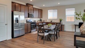 Una cocina moderna con armarios de madera, electrodomésticos de acero inoxidable y un comedor con mesa y sillas.