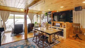 Una cabaña con interior de madera, un comedor con mesa y sillas, un televisor y vistas a un lago.
