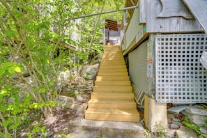 A wooden staircase leading to a building with a white lattice fence and a wooden roof.