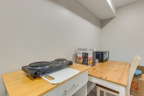 Eine Küchenzeile mit Kaffeemaschine, Mikrowelle und Schneidebrett auf einem Holztisch.