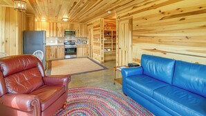 Een houten interieur met een bank, een stoel, een kitchenette en een opbergmeubel.