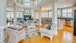 A spacious living area with wicker furniture, a fireplace, and a kitchen with stainless steel appliances. - Walk to Beach! Spacious Surf City Escape (Surf City)