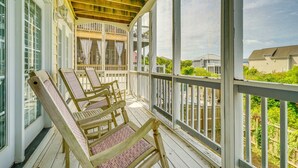 A covered porch with wooden chairs and a railing, overlooking a residential area. - Walk to Beach! Spacious Surf City Escape (Surf City)