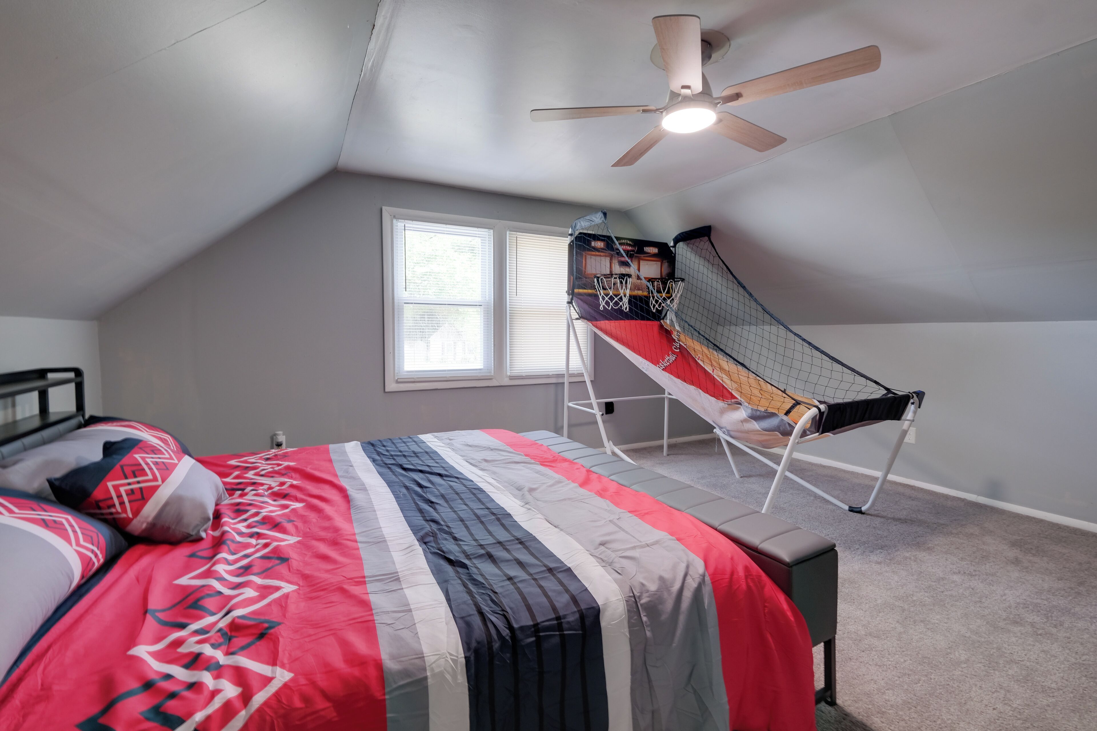 Une chambre à coucher avec un lit, un ventilateur de plafond, une fenêtre et un panier de basket.
