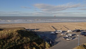 Ein Strand mit geparkten Autos und einer Düne.