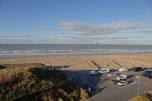 Ein Strand mit geparkten Autos und einer Düne.