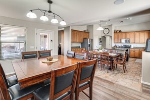A spacious kitchen with wooden cabinets, a large dining table, and a modern chandelier. - Spacious Backyard! Family Haven in San Tan Valley (San Tan Valley)