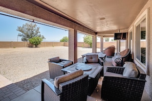 An outdoor patio with wicker furniture, a table, and a TV. - Spacious Backyard! Family Haven in San Tan Valley (San Tan Valley)