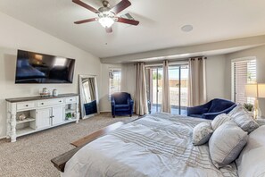 A bedroom with a bed, a ceiling fan, a TV, a dresser, a chair, and a window with curtains. - Spacious Backyard! Family Haven in San Tan Valley (San Tan Valley)
