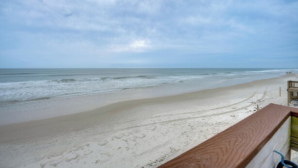 Blick auf einen Strand mit Holzwertung, Sand und Meer.