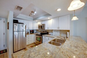 Eine moderne Küche mit weißen Schränken, Edelstahlgeräten, einer Granitarbeitsplatte und einem eingebauten Backofen.