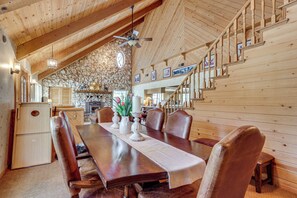 A wooden dining area with a table, chairs, a ceiling fan, and a stone wall. - 25-Acre Hideaway in Oakhurst: Pet Friendly! (Oakhurst)