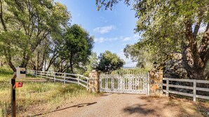 A gravel path leading to a gated entrance with a white fence and a stone wall. - 25-Acre Hideaway in Oakhurst: Pet Friendly! (Oakhurst)