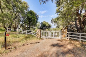 A gravel path leading to a gated entrance with a white fence and a stone wall. - 25-Acre Hideaway in Oakhurst: Pet Friendly! (Oakhurst)