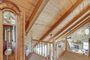 A wooden interior with a large clock, wooden beams, a stone wall, and a staircase. - 25-Acre Hideaway in Oakhurst: Pet Friendly! (Oakhurst)