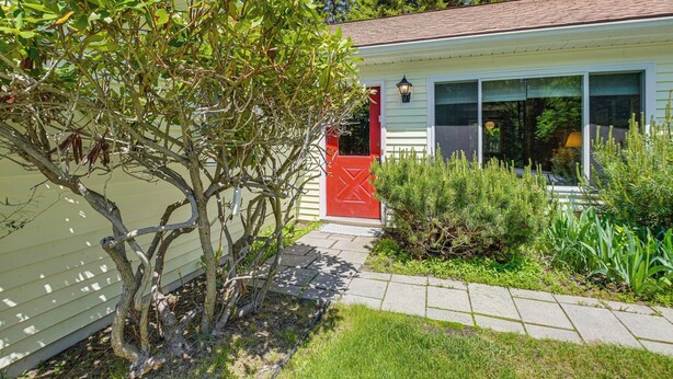 A house with a red door, a small garden, and a pathway leading to the entrance. - Kenway Ranch: Family Retreat Near Acadia Trails (Southwest Harbor)