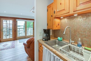 A kitchen with wooden cabinets, a stainless steel sink, and a coffee maker. - Waterfront Maine Hideaway: 14 Mi to Quoddy Head (Lubec)