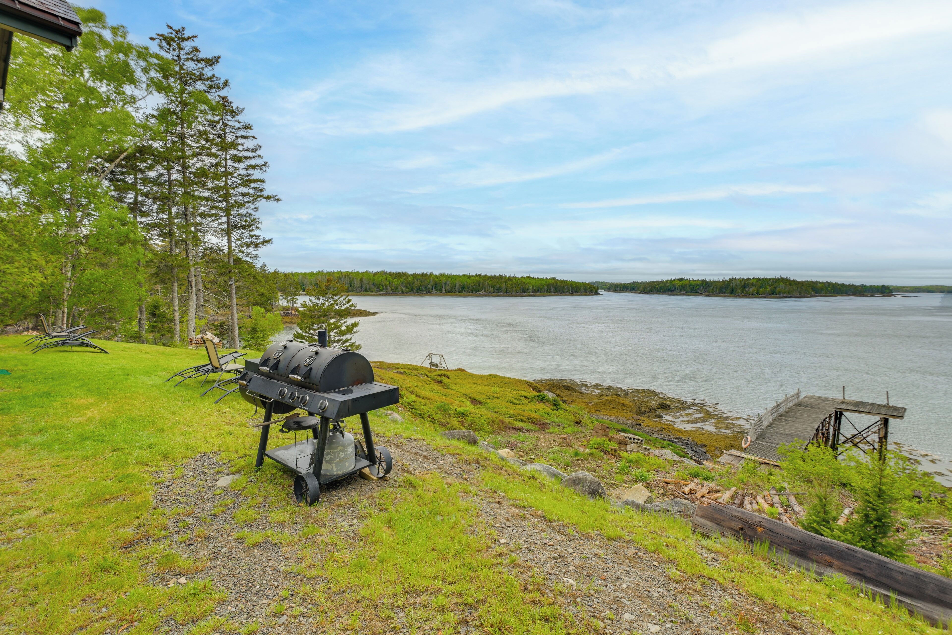 A lakeside view with a grill and dock.