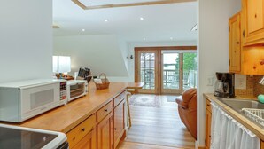 Une cuisine avec des meubles en bois, un four à micro-ondes, une machine à café et une vue sur l’extérieur.