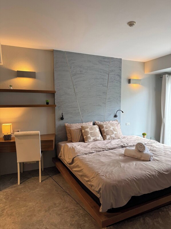 Une chambre à coucher moderne avec un lit, des tables de chevet, un bureau et une chaise.