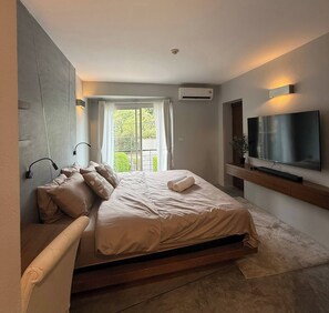 Une chambre à coucher moderne avec un lit, une télévision et une fenêtre avec des rideaux.