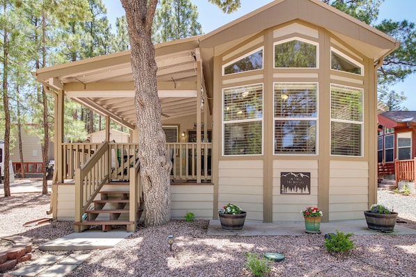 A lodge with a covered porch, a staircase, and a large window. - Fairways, Fishing & Forest Fun! Show Low Retreat (Show Low)