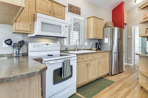 A kitchen with wooden cabinets, a stainless steel refrigerator, a microwave, and a stove. - Fairways, Fishing & Forest Fun! Show Low Retreat (Show Low)