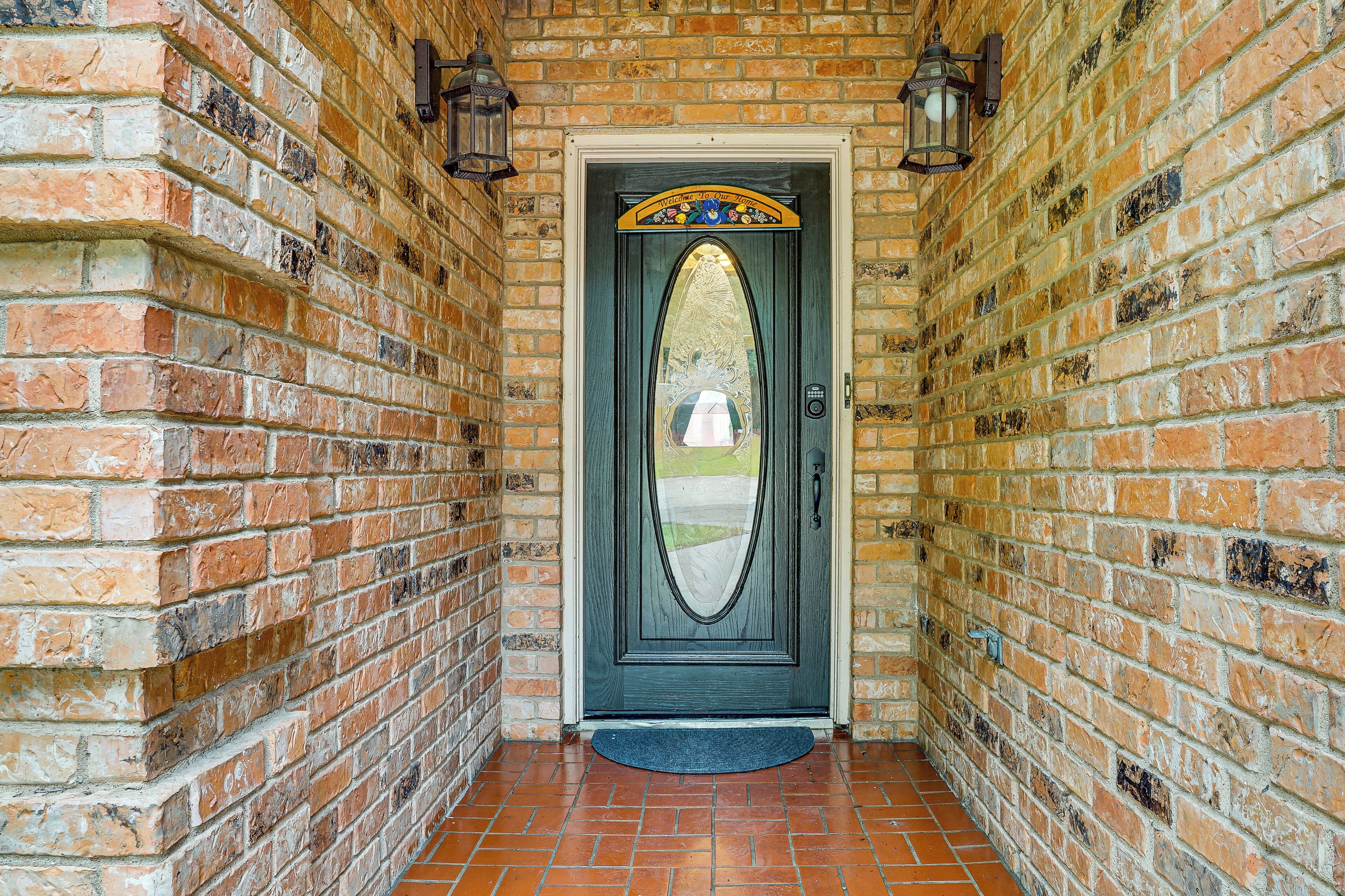 A brick wall with a door featuring a decorative arch and a doormat.
