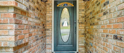 A brick wall with a door featuring a decorative arch and a doormat.