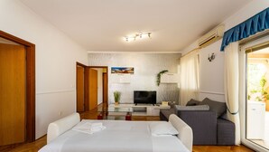 Ett hotellrum med en säng, en soffa, en tv och ett matbord.