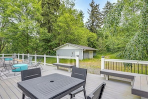 Eine Terrasse mit Gartenmöbeln, eine kleine Gartenhütte und ein weißer Zaun.