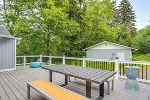 Eine Holzterrasse mit Tisch und Bank, umgeben von weißen Geländern und Bäumen.