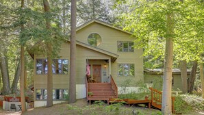 A two-story house with a front porch, a circular window, and a flag. - Glen Arbor Home w/ Glen Lake Access & Shared Dock! (Glen Arbor)