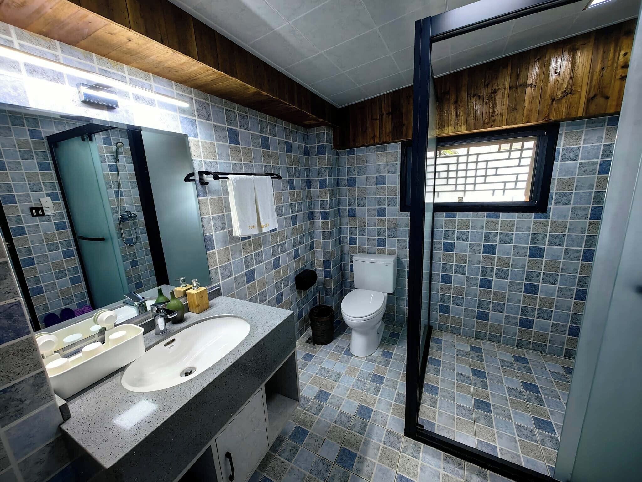 A bathroom with a tiled floor, a sink, a toilet, and a shower area.