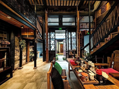 A traditional interior with wooden beams, a central staircase, and a view to the outside.. Dream Country Qiankou Resort