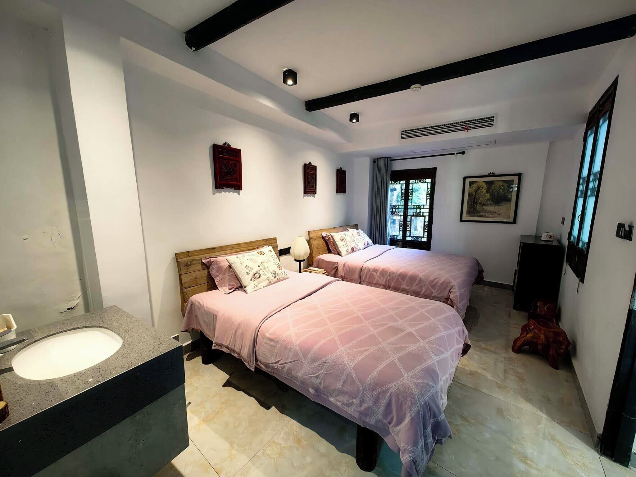 A bedroom with two beds, a bathroom with a sink, and a window with a view.