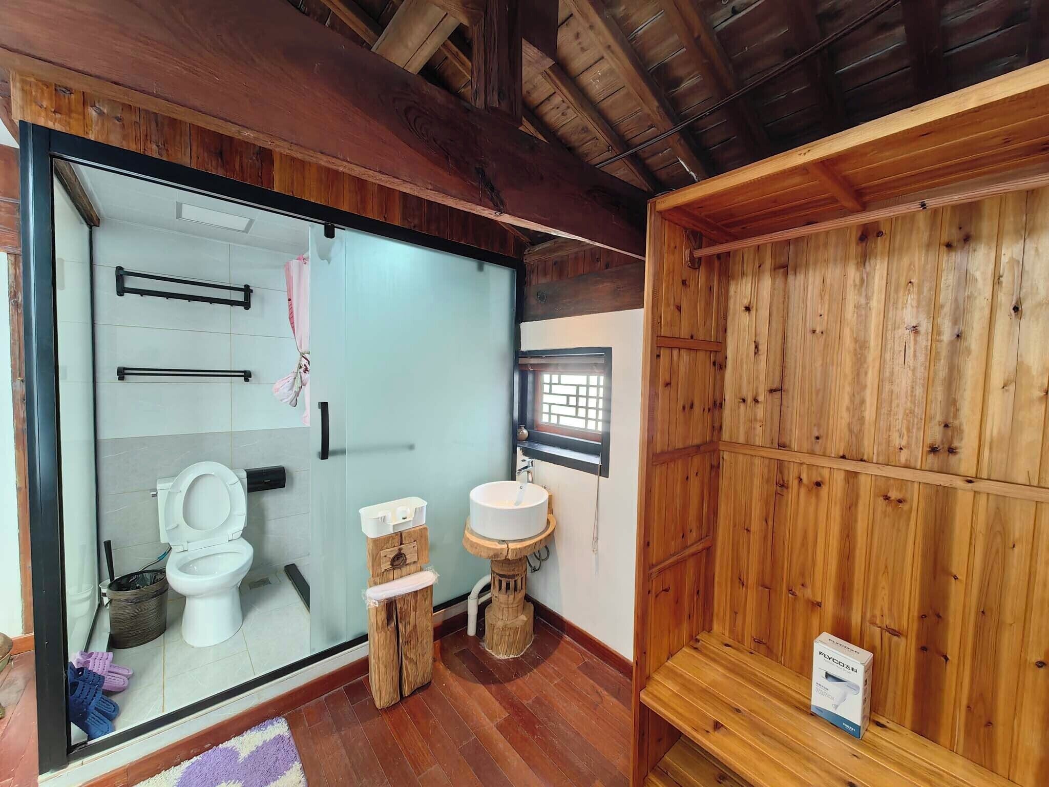 Une salle de bain avec des toilettes, un lavabo et des étagères en bois.