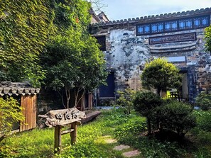 Un edificio tradicional con un patio, estructuras de madera y vegetación.