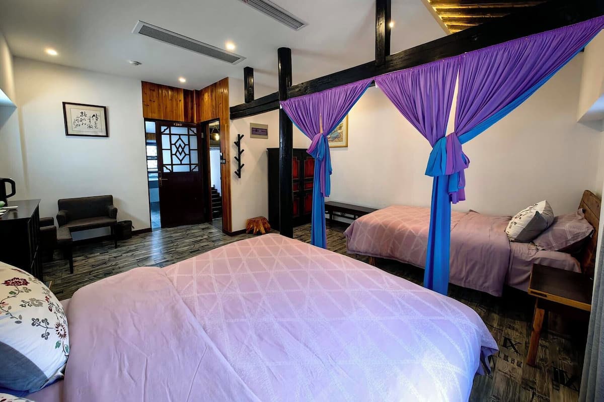 A hotel room with two beds, a sofa, a desk, and a wooden ceiling.