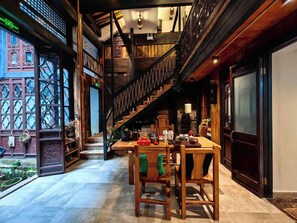 Un interior de madera con una escalera, una mesa con sillas y vistas al exterior.