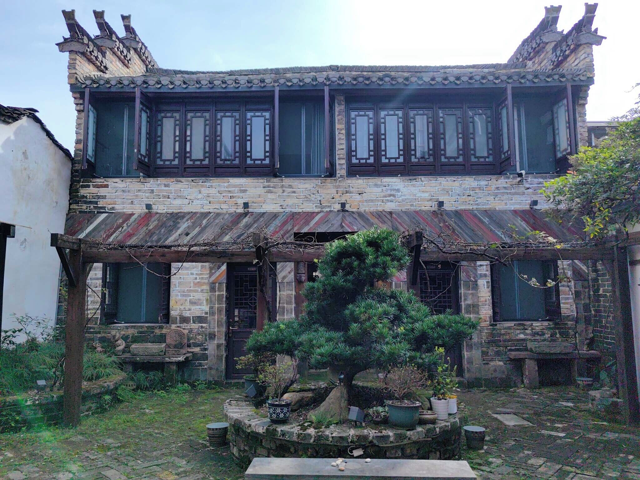 A traditional building with a tiled roof, wooden window frames, and a stone staircase leading to the entrance.