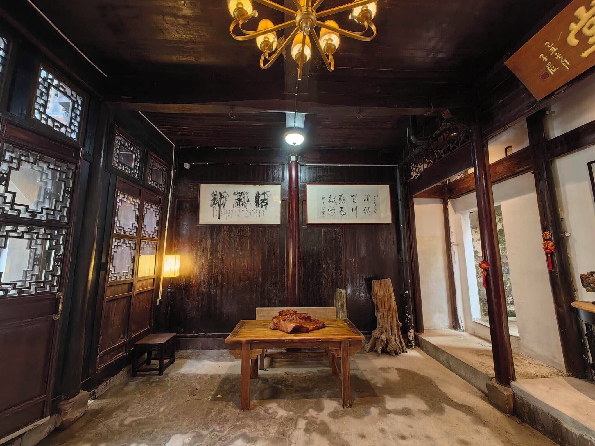 Una habitación tradicional con paredes de madera, una mesa con comida y caligrafía china en la pared.
