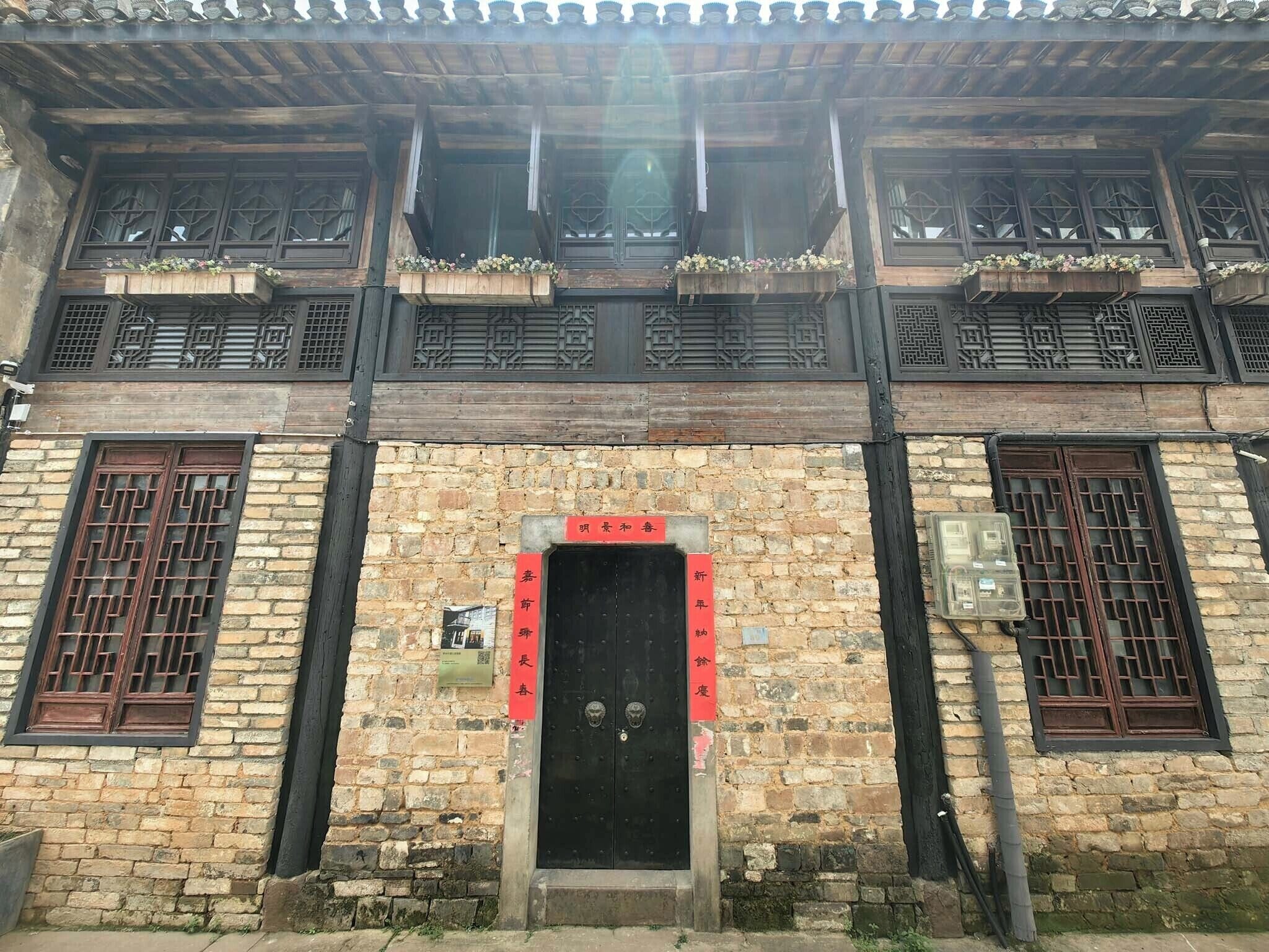 Un edificio tradicional con fachada de madera, una puerta negra y rejas decorativas en las ventanas.